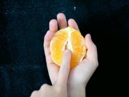person holding sliced orange fruit