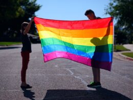man and girl holding rainbow flag