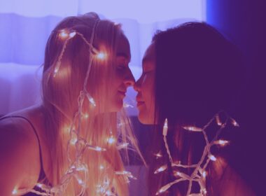 two woman facing each other with string lights