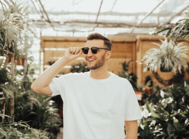 man in white crew-neck shirt wearing sunglasses standing near plants