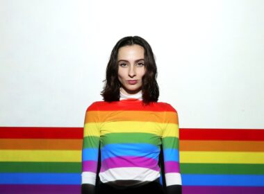 a woman standing in front of a rainbow colored wall