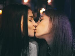 two women kissing each other in a dark room