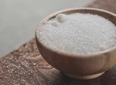 a wooden bowl filled with sugar on top of a wooden table