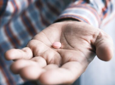 person holding pink round medication pill